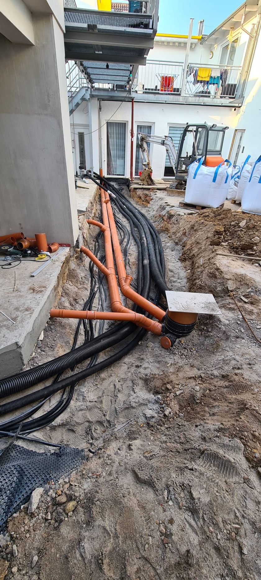 Erdarbeiten mit neu verlegten Leitungen an einem Gebäude in Mainz